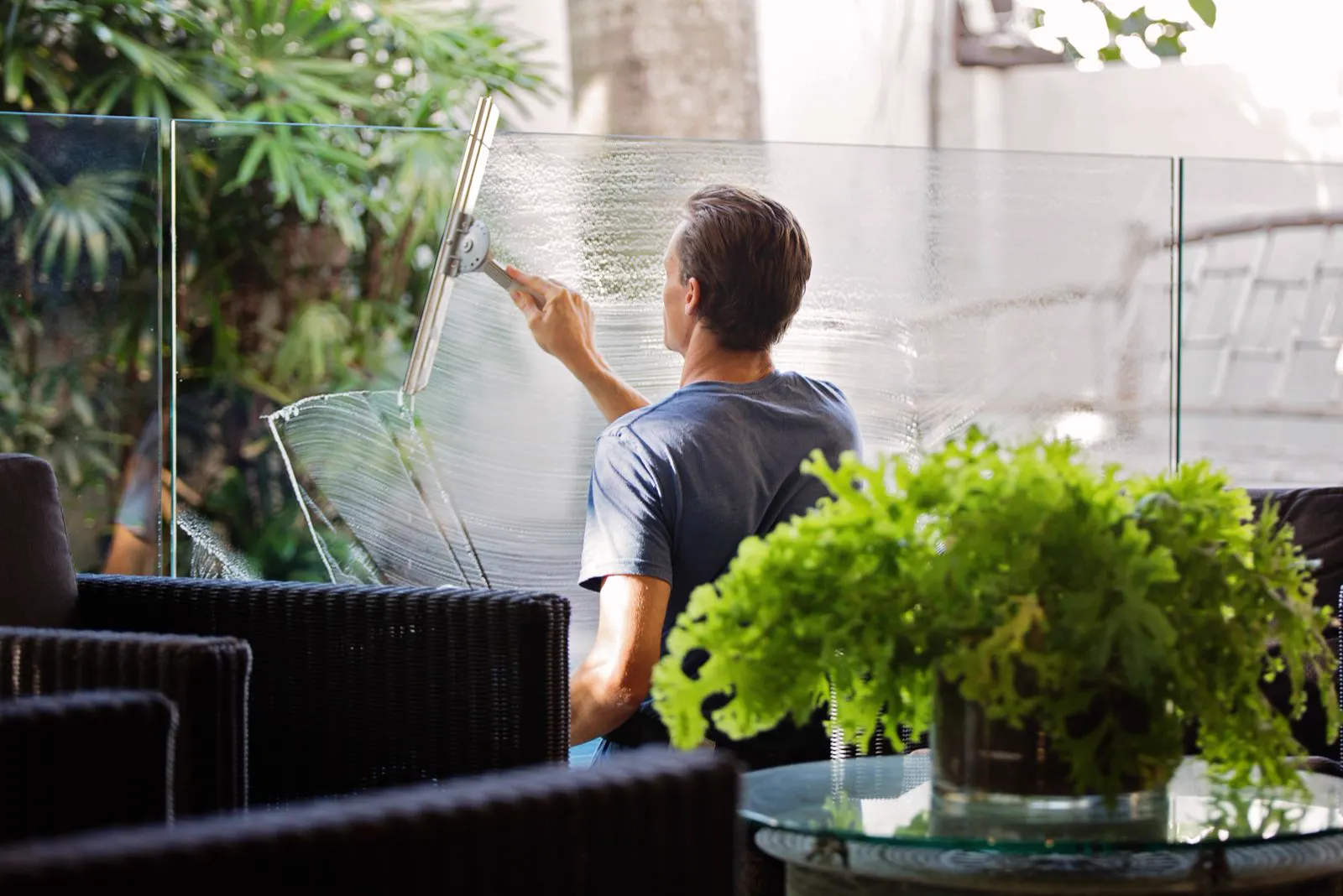 Worker pulling a squeegee across a large pane of soapy glass